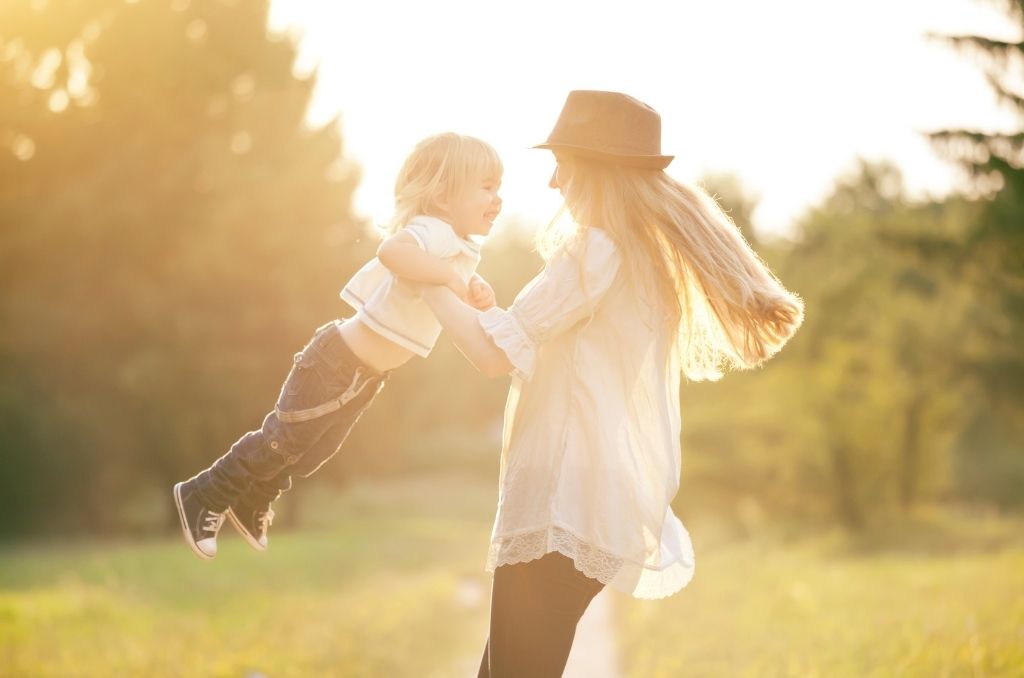 Kobieta bawiąca się z dzieckiem na słońcu – symbol świadomego planowania płodności i możliwości macierzyństwa dzięki zabezpieczeniu komórek jajowych.