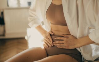 Kobieta dotykająca podbrzusza jako symbol obserwacji cyklu i procesów związanych z owulacją.