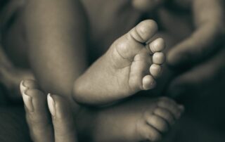 Noworodek w dłoniach rodziców – efekt leczenia niepłodności i spełnienie marzenia o dziecku.