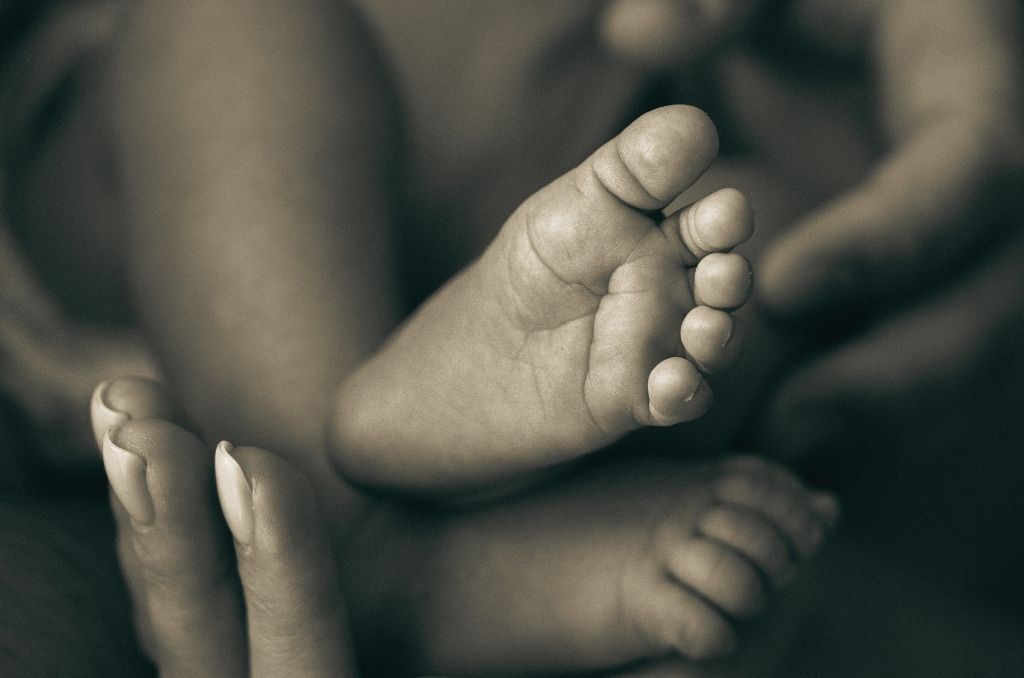 Noworodek w dłoniach rodziców – efekt leczenia niepłodności i spełnienie marzenia o dziecku.